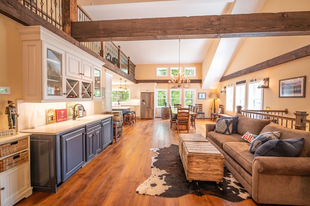 living room featuring hardwood / wood-style flooring, high vaulted ceiling, a notable chandelier, wet bar, and beamed ceiling