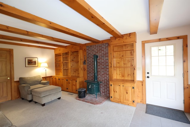 carpeted living room featuring brick wall, beamed ceiling, and a wood stove