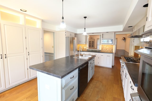 kitchen featuring white cabinets, stainless steel appliances, a kitchen island with sink, and sink