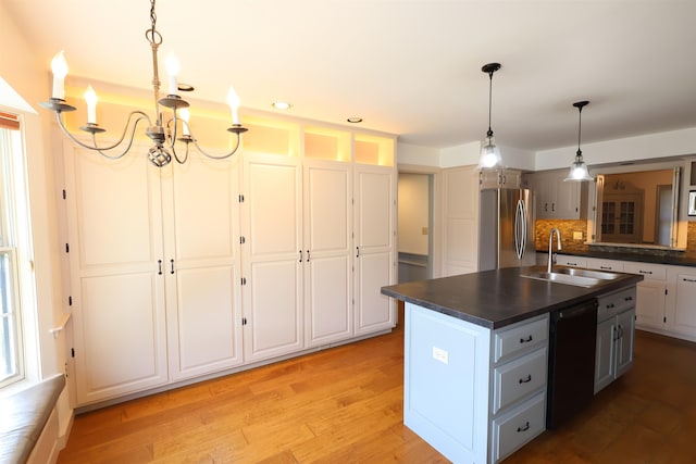 kitchen with sink, dishwasher, a center island with sink, stainless steel refrigerator, and backsplash