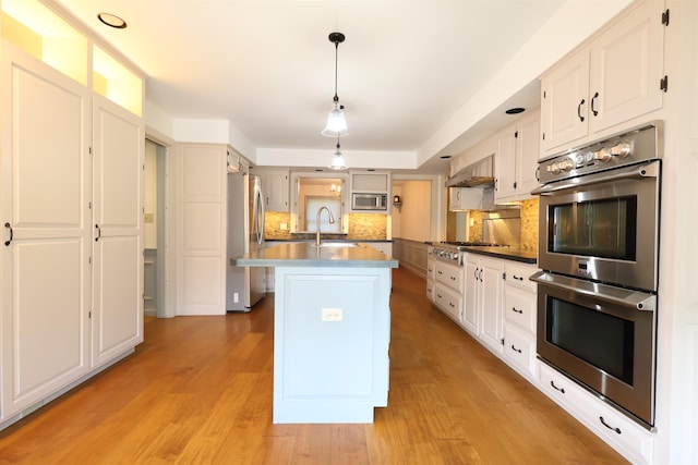 kitchen with tasteful backsplash, stainless steel appliances, white cabinets, sink, and light hardwood / wood-style floors