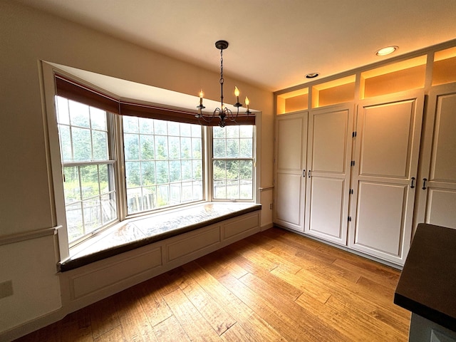 unfurnished dining area featuring an inviting chandelier and light hardwood / wood-style flooring