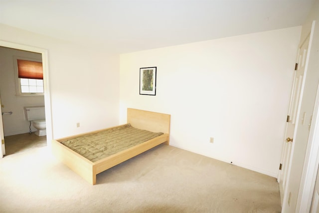 unfurnished bedroom featuring light carpet and ensuite bathroom