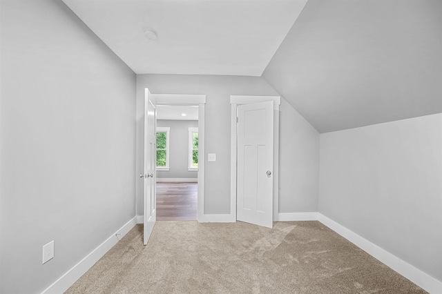 bonus room featuring lofted ceiling and light colored carpet