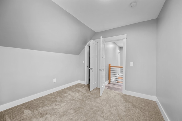 bonus room with vaulted ceiling and light colored carpet