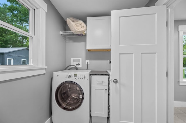 clothes washing area with cabinets, washer / dryer, and light tile patterned floors