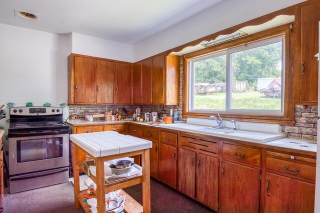 kitchen featuring backsplash, carpet floors, electric stove, tile countertops, and sink