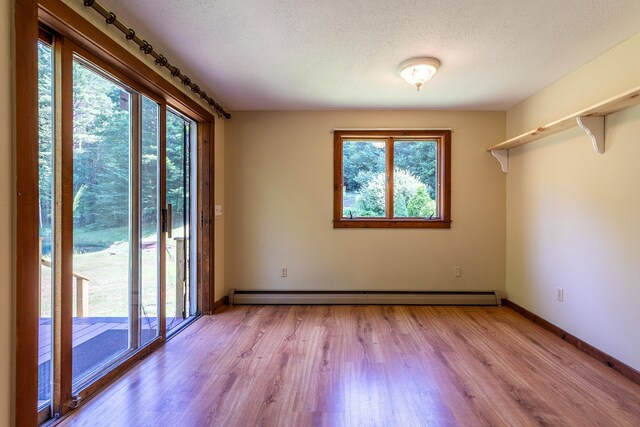 carpeted empty room with ceiling fan, a wealth of natural light, and a baseboard radiator