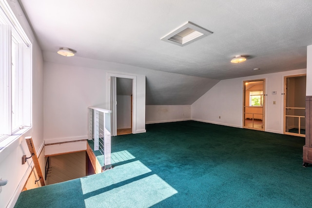 bonus room with a textured ceiling, lofted ceiling, and dark colored carpet