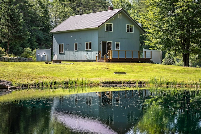 back of house with a lawn and a deck with water view