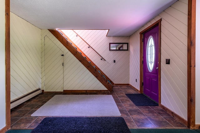 foyer entrance with a textured ceiling, wooden walls, and a baseboard heating unit