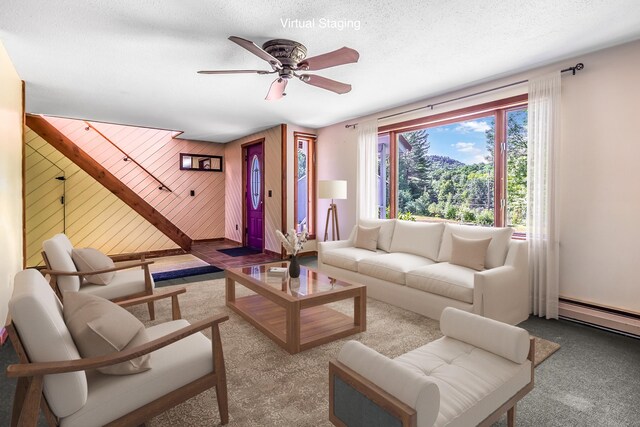 living room featuring wood walls, ceiling fan, baseboard heating, light carpet, and a textured ceiling