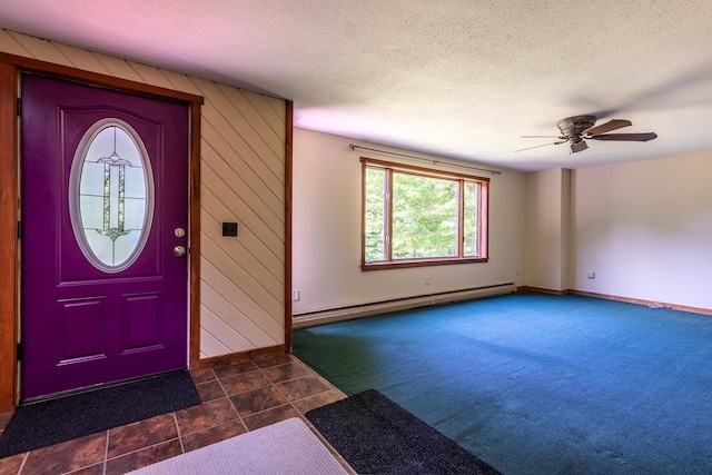 carpeted foyer with ceiling fan, a baseboard radiator, wood walls, and a textured ceiling