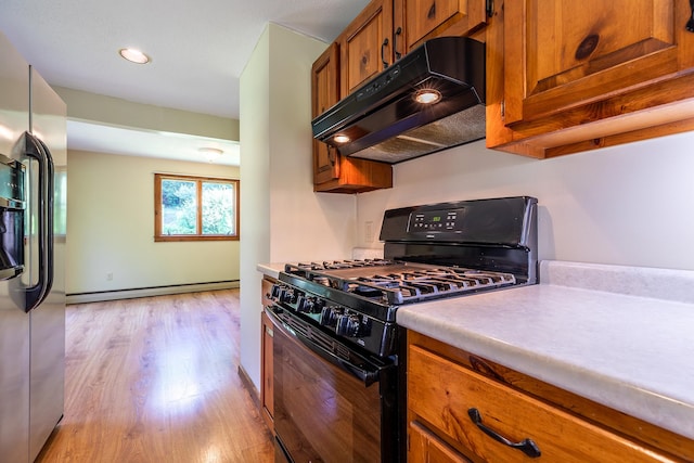 kitchen featuring black gas range, light wood-type flooring, stainless steel fridge, and baseboard heating