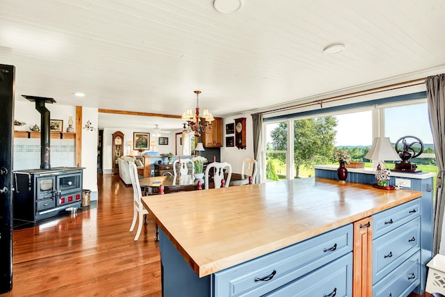 kitchen featuring dark hardwood / wood-style floors, blue cabinets, wood counters, decorative light fixtures, and a wood stove