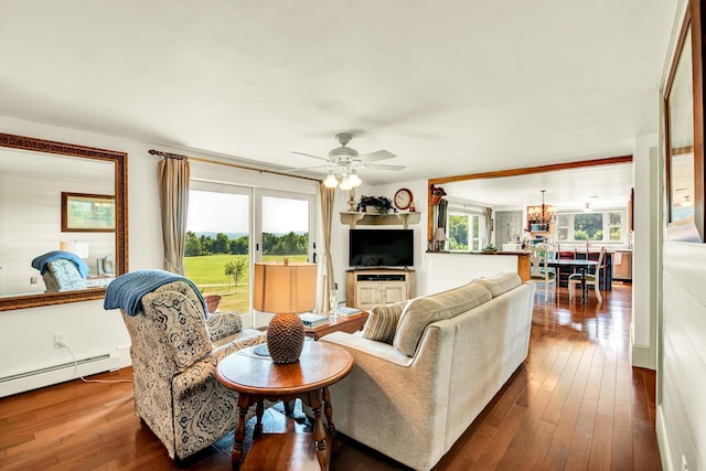 living room with ceiling fan with notable chandelier, a baseboard heating unit, and hardwood / wood-style floors