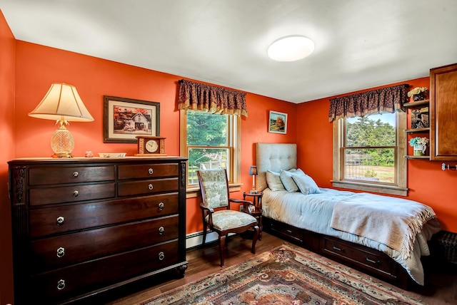 bedroom featuring a baseboard radiator, hardwood / wood-style floors, and multiple windows