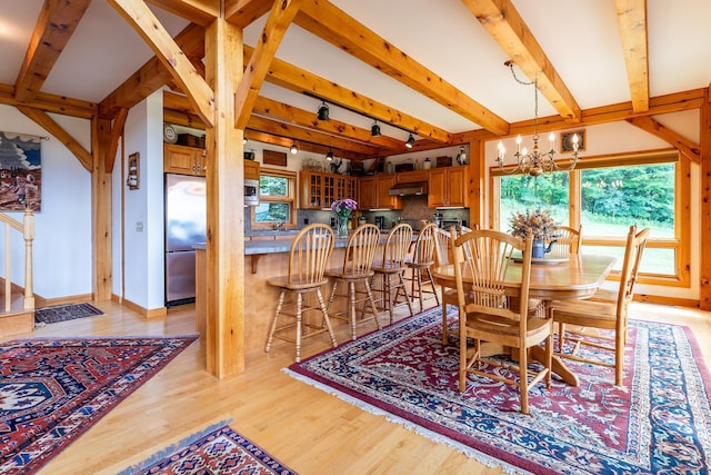 dining area with an inviting chandelier, track lighting, light hardwood / wood-style floors, and beamed ceiling