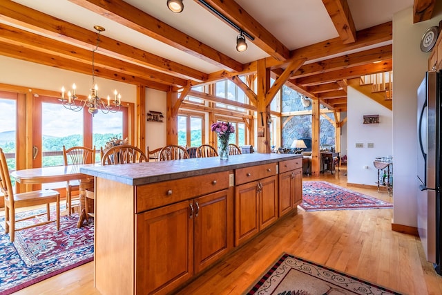 kitchen featuring stainless steel fridge, hanging light fixtures, a center island, a chandelier, and light wood-type flooring