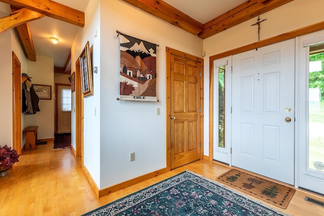 foyer featuring light wood-type flooring and beam ceiling