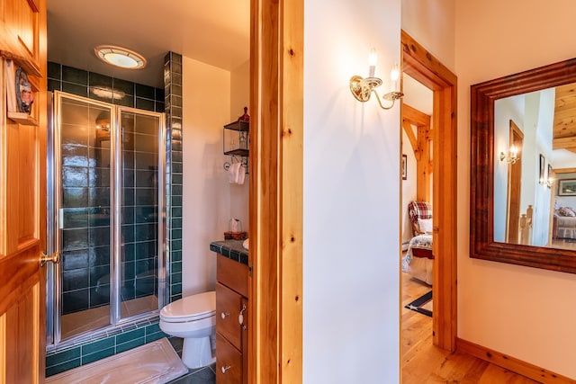 bathroom with vanity, hardwood / wood-style flooring, a shower with door, and toilet