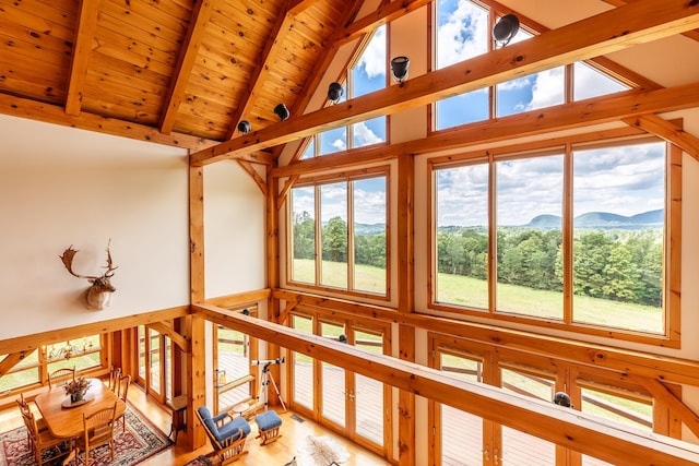 unfurnished sunroom with a mountain view, lofted ceiling with beams, and wooden ceiling