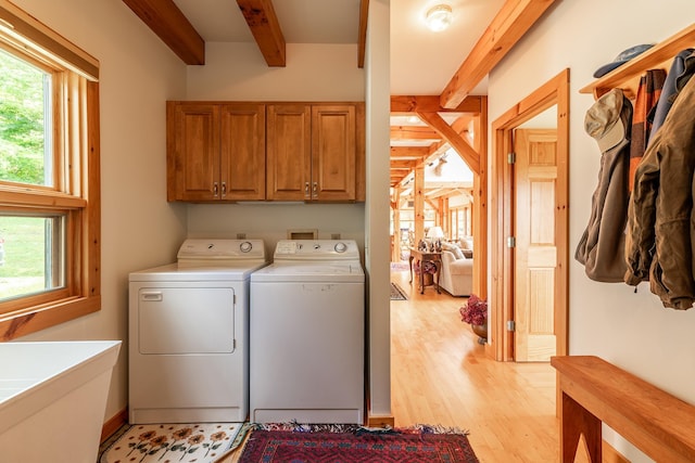 laundry room featuring light hardwood / wood-style floors, cabinets, and washing machine and clothes dryer