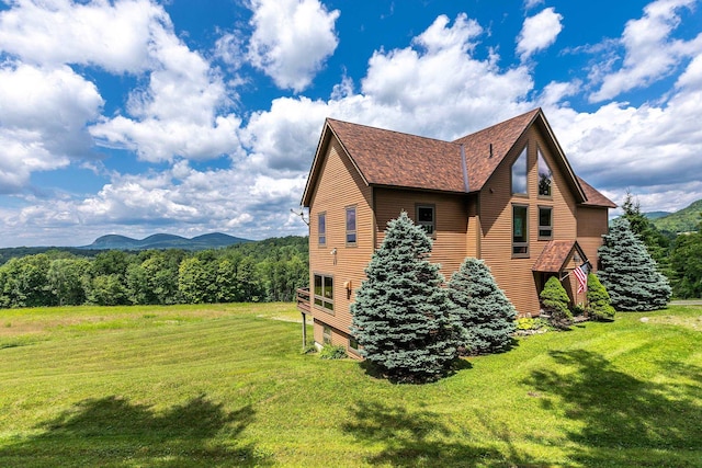 view of property exterior with a mountain view and a lawn