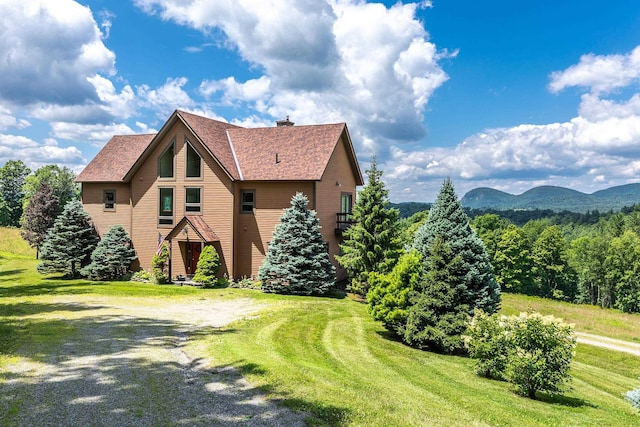 view of side of home with a mountain view and a yard