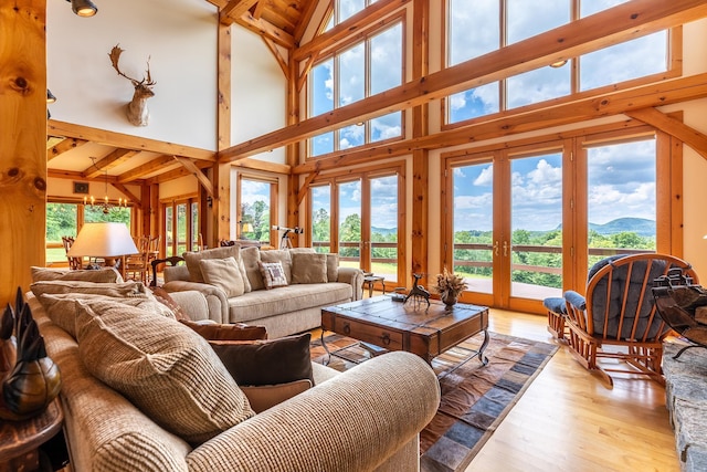 living room featuring vaulted ceiling with beams, light hardwood / wood-style floors, a mountain view, french doors, and a chandelier