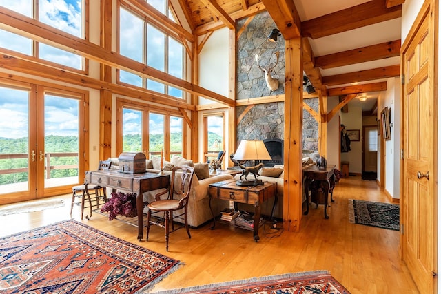 living room featuring a stone fireplace, light hardwood / wood-style flooring, and lofted ceiling with beams