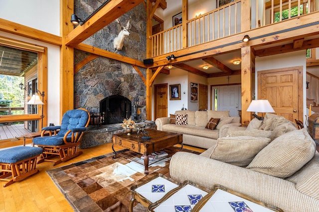 living room featuring a stone fireplace, hardwood / wood-style floors, and a high ceiling