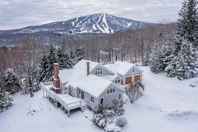 snowy aerial view featuring a mountain view and a view of trees