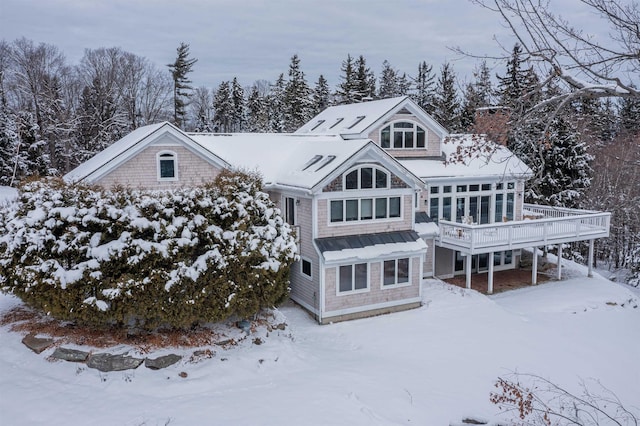 snow covered back of property featuring a deck