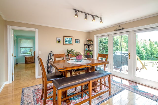 dining room featuring crown molding, plenty of natural light, track lighting, and light hardwood / wood-style flooring