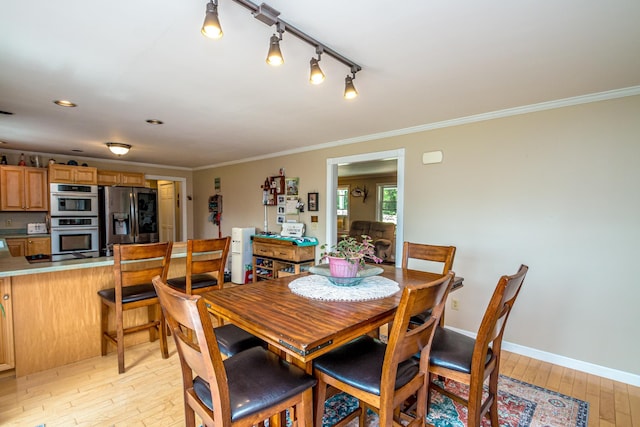 dining area with ornamental molding, rail lighting, and light hardwood / wood-style flooring