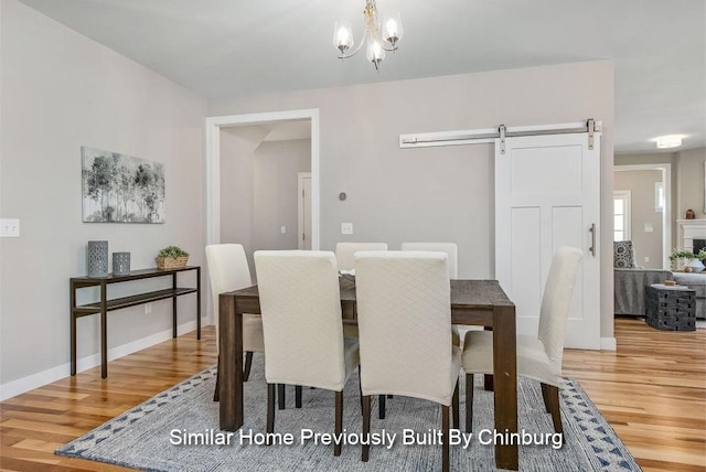 dining area with an inviting chandelier, a barn door, and hardwood / wood-style flooring