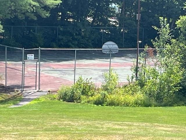 view of tennis court featuring a yard and basketball hoop