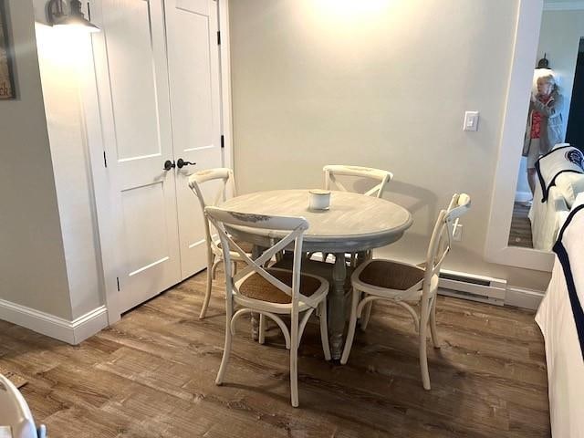 dining area featuring wood-type flooring and a baseboard heating unit