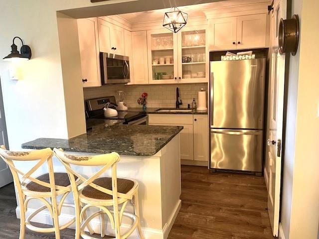 kitchen with kitchen peninsula, backsplash, dark hardwood / wood-style floors, stainless steel appliances, and sink