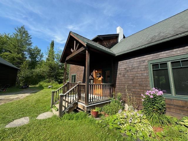 exterior space with a yard, a porch, and a chimney