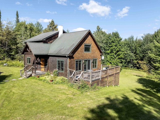 back of house with a deck, a yard, and a chimney