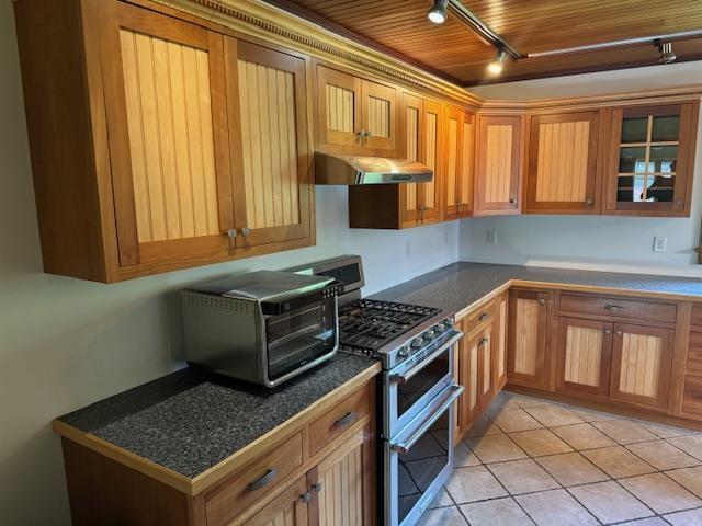 kitchen with wood ceiling, glass insert cabinets, ventilation hood, double oven range, and light tile patterned flooring