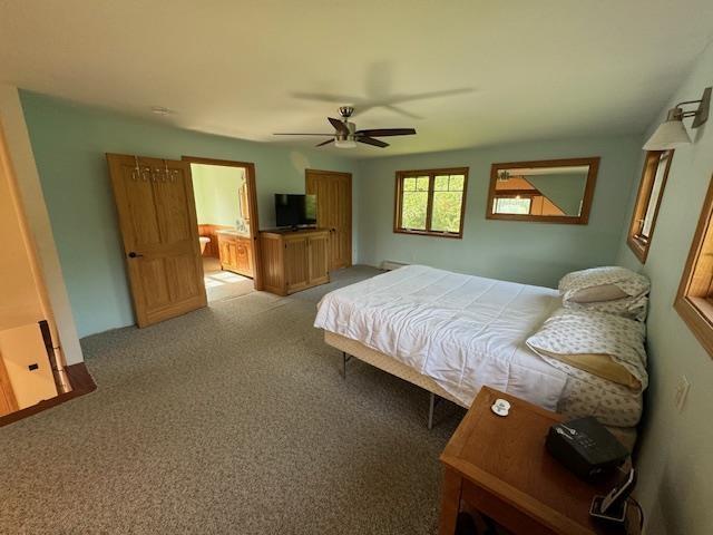 carpeted bedroom with ceiling fan and connected bathroom