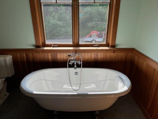 interior details featuring a soaking tub and wainscoting