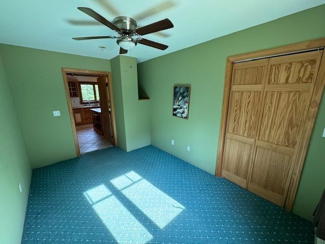 unfurnished bedroom with a ceiling fan, a closet, and light carpet