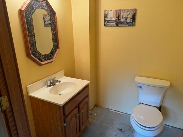 half bathroom with toilet, concrete floors, and vanity