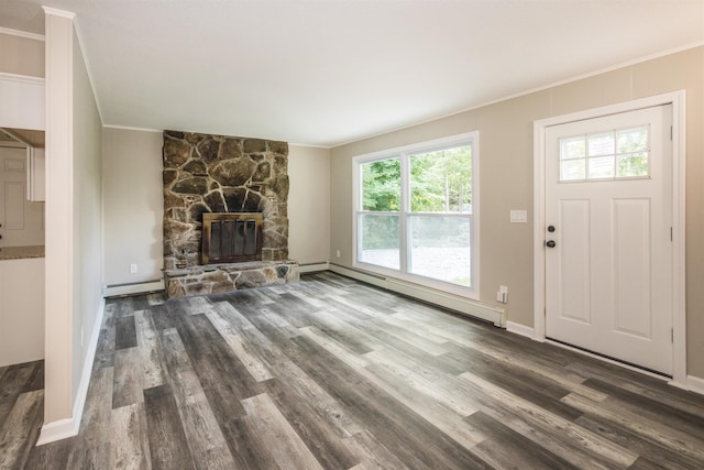 unfurnished living room with dark hardwood / wood-style floors, a stone fireplace, and a baseboard heating unit