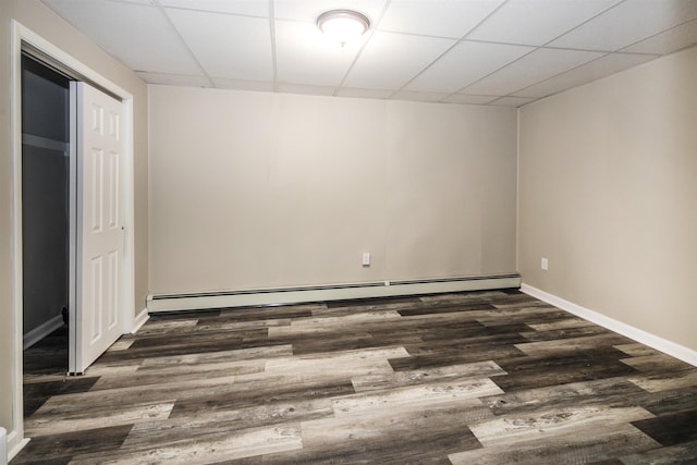 spare room with dark wood-type flooring, a baseboard heating unit, and a drop ceiling