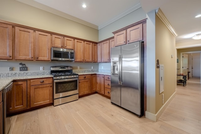 kitchen featuring stainless steel appliances, brown cabinets, light stone countertops, and crown molding